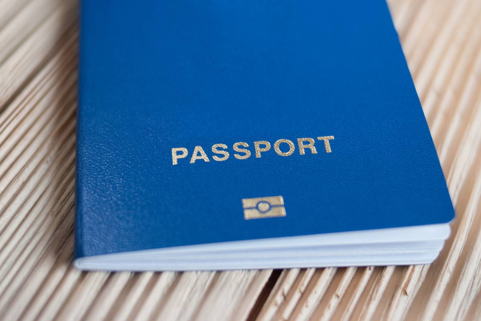 A blue passport with gold lettering placed on a wooden surface