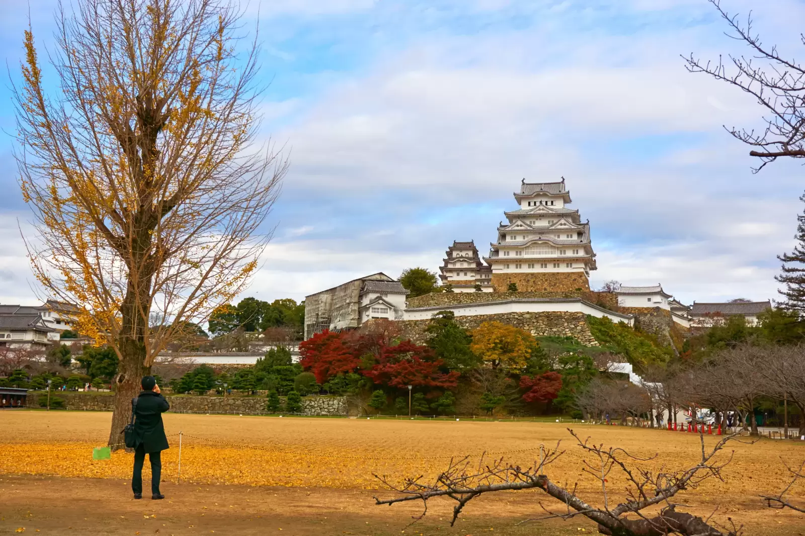 man stands and takes a photo of himeji castle in cloudy day