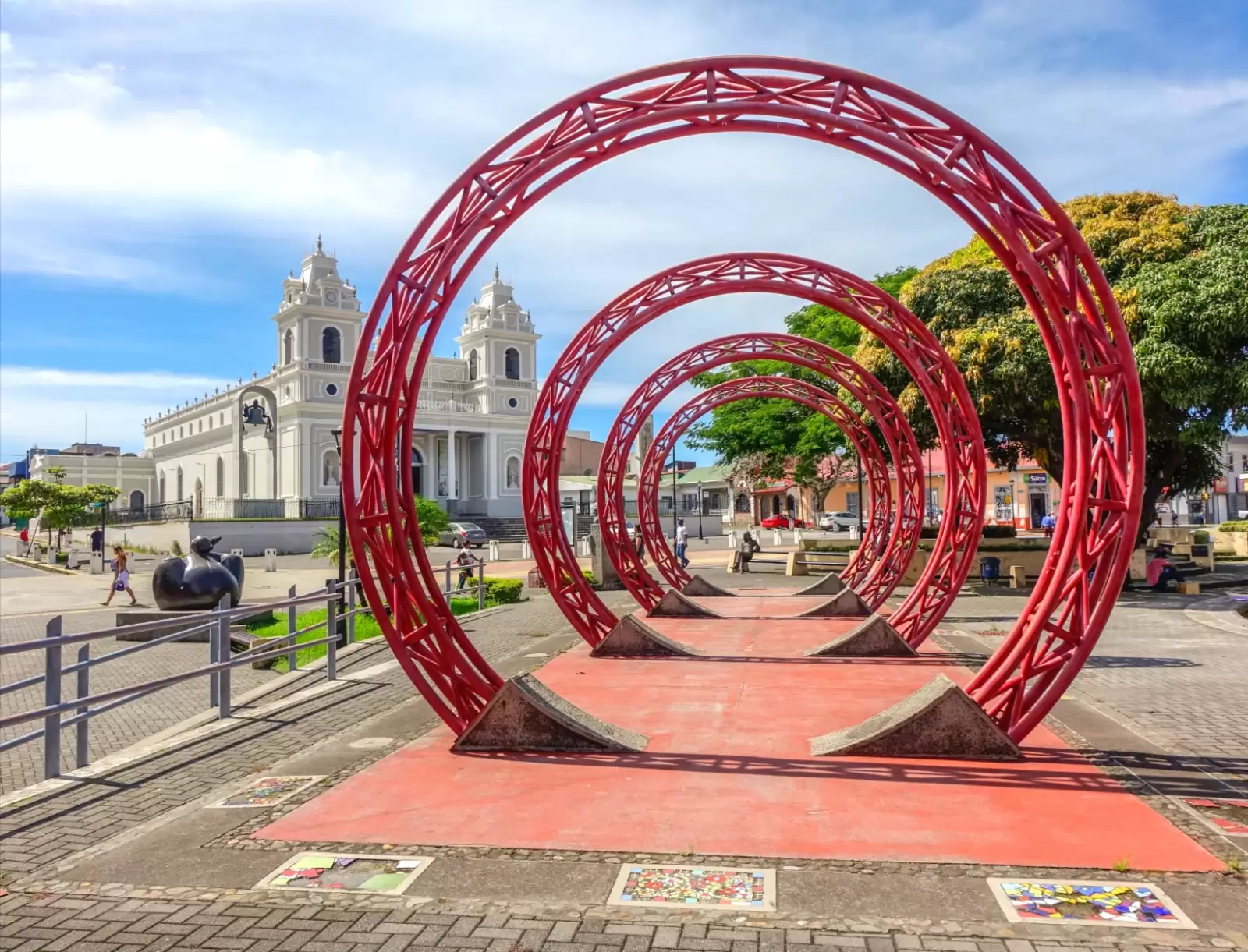 sculpture of red rings in the middle of a square with a church